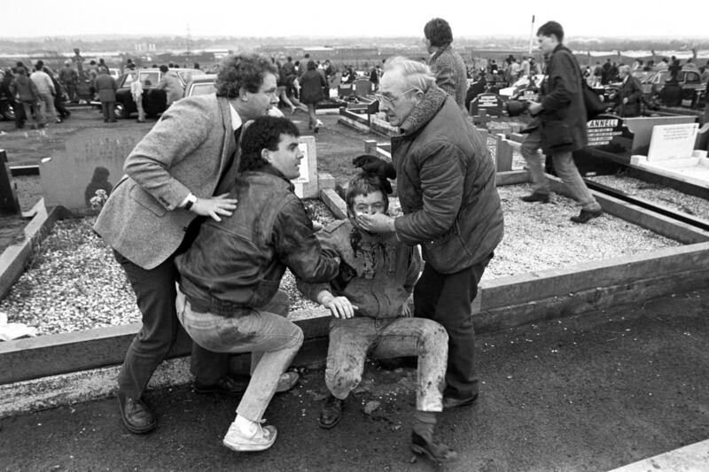An injured man being aided by mourners, including Sinn Fein vice president Martin McGuinness (left), at Milltown Cemetery, Belfast, after a gun and bomb attack killed three and left four seriously injured, at the funerals in 1988 of three IRA members killed in Gibraltar.  David Jones/PA Wire