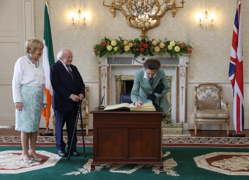 Michael D Higgins and his wife Sabina watch as Princess Anne signs a visitor book at Áras an Uachtaráin. Photograph: Gareth Chaney/PA