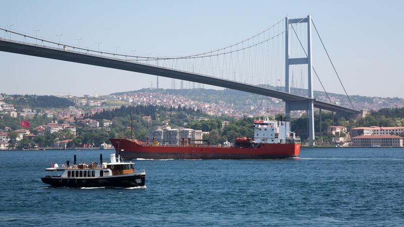 Freight ship and pleasure boat passing under the Bosphorus Bridge in Istanbul.