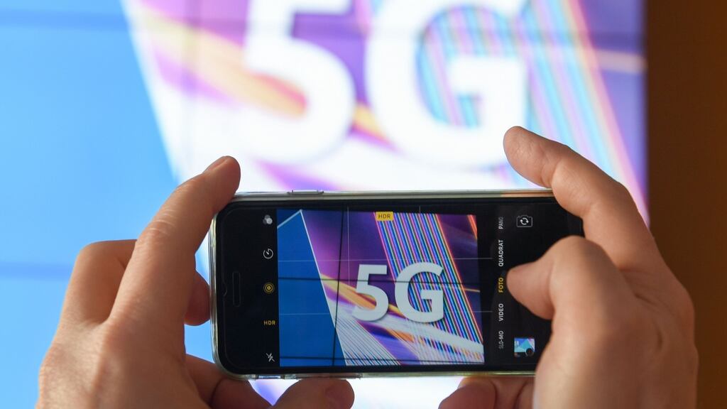 A journalist takes pictures of a projection screen prior to the start of Germany’s auction for the construction of an ultra-fast 5G mobile network on March 19, 2019 at the German Federal Network Agency(Photo by Arne Dedert / dpa / AFP)