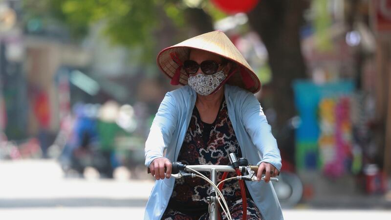 A woman wearing a face mask rides a bicycle in Hanoi. Photograph: Hau Dinh/AP