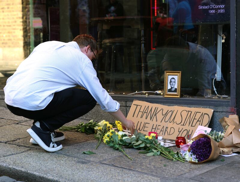 A person lighting a candle in tribute to Sinead O'Connor at the Irish Rock 'n' Roll Museum in the Temple Bar area of Dublin. Photograph: Damien Eagers/PA Wire