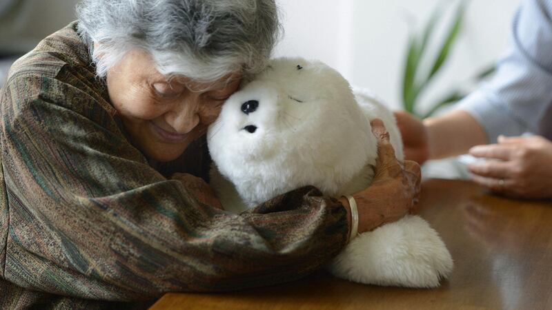 An elderly woman holds a seal-shaped therapy robot. Photograph:  Kyodo News via Getty Images