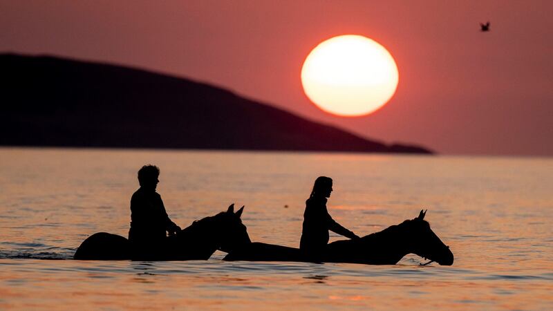Hanna McDowell on her horse,  Hero, and Jenny Doran on her horse, Neo, exercising  in the sea at sunrise at Portmarnock Beach, Portmarnock, Co Dublin, on Sunday. Photograph: Tom Honan