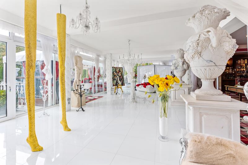 Sunroom with sculptures (including golden legs), white marble floor and access to the wide terrace