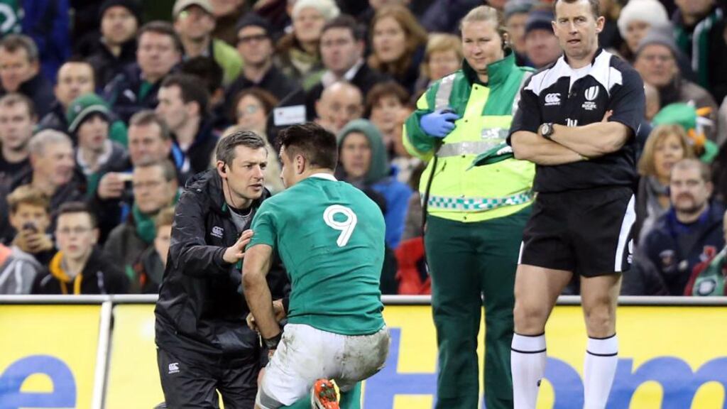 Ireland physio Keith Fox assesses Conor Murray before leading him  from the pitch late in the game against Australia. Photo: Colm O’Neill/Inpho.