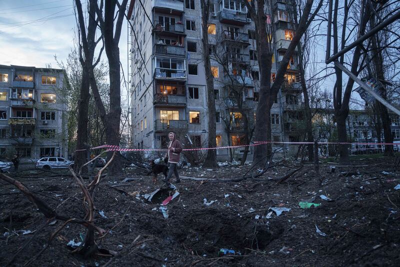 A woman walks a dog at the scene of a Russian strike on residential area in Kyiv. Photograph: Evgeniy Maloletka/AP