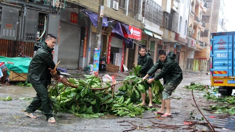 People try to remove a bough from a street as Typhoon Mujigae hits Maoming, Guangdong province. Photograph: Stringer/Reuters