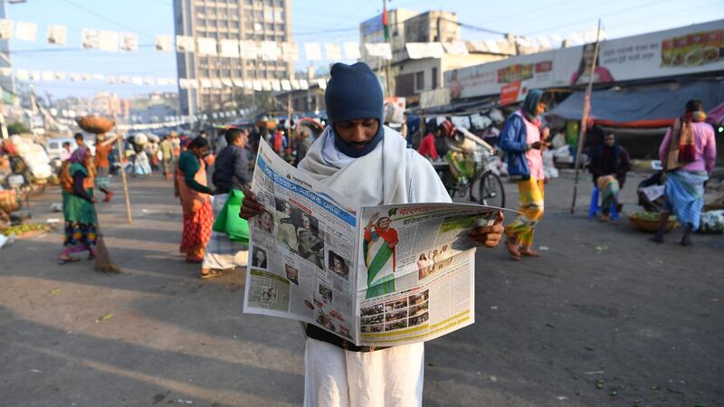 A man reads a newspaper carrying headlines of the general election results in Dhaka on New Year’s Eve. Photograph:  Indranil Mukerjee/ AFP/Getty Images