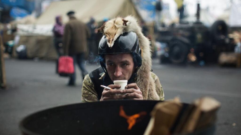A member of a civilian defence unit warms up by a fire at Independence Square in Kiev today. Photograph: Uriel Sinai/The New York Times