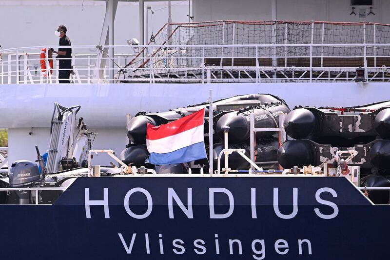 A Dutch flag flies as a crew member wearing a face mask assists the docking as the MV Hondius arrives at the port of Rotterdam on May 18th, 2026. Photograph: JOHN THYS/AFP via Getty Images