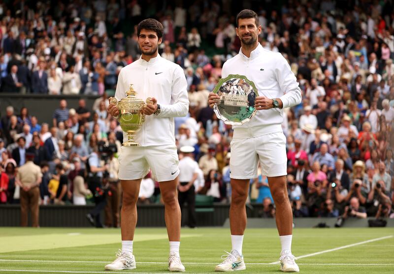 Carlos Alcaraz holds the men's singles trophy alongside Novak Djokovic with the men's singles runner's up plate at Wimbledon. Photograph: Julian Finney/Getty