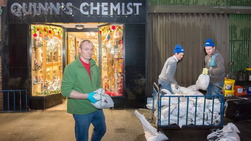 Darragh Quinn owner of Quinn’s Chemist in Crossmolina clears away sand bags that failed to prevent flood waters coming in to his shop. Photograph:  Michael McLaughlin