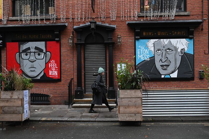 A woman walks past a mural depicting Andy Burnham and Boris Johnson, then UK prime minister, on the front of a closed pub in Manchester during a second national coronavirus lockdown. Photograph: Oli Scarff/AFP via Getty 