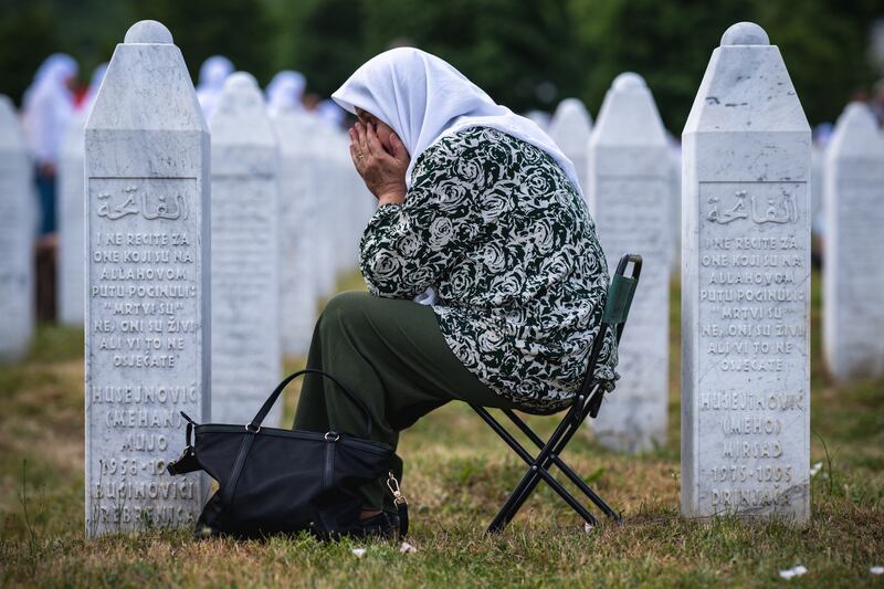 A woman reacts as she sits among gravestones at the memorial cemetery in the village of Potocari on the 30th anniversary of the Srebrenica massacre. Photograph: Andrej Isakovic/AFP      