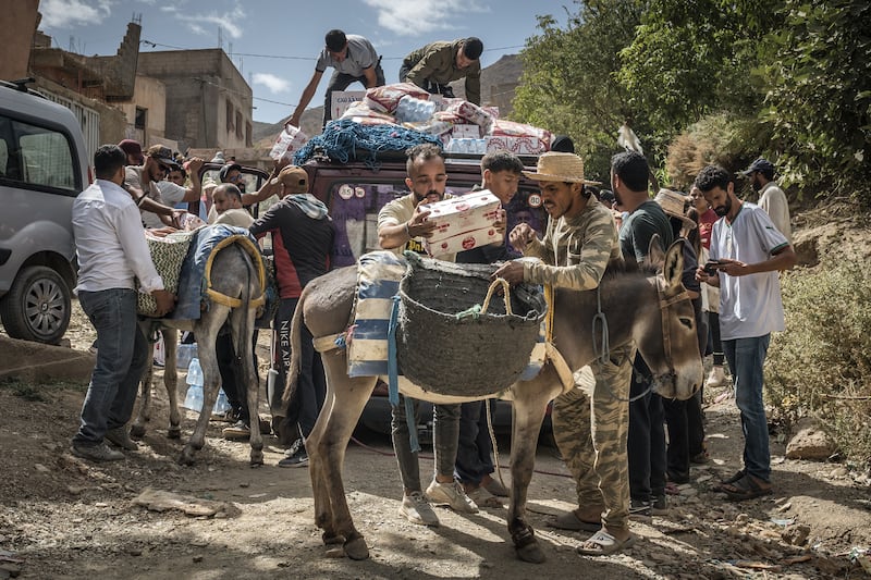 People load aid on to donkeys to transport it to Douar Tnirt village in the hard-hit Al Haouz province in Morocco. Photograph: Sergey Ponomarev/New York Times