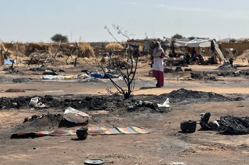 A displaced Sudanese woman who left El-Fasher after its fall with others, walks amid the remains of a fire that broke out at a camp in Tawila on February 11, 2026. Photograph: AFP via Getty Images