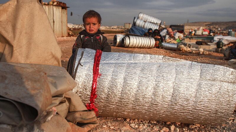 A child stands behind a rolled-up thermal insulation foil at a camp for displaced Syrians east of Sarmada in  Idlib province on Sunday, as people prepare to flee the camp. Photograph: Aaref Watad/AFP via Getty Images