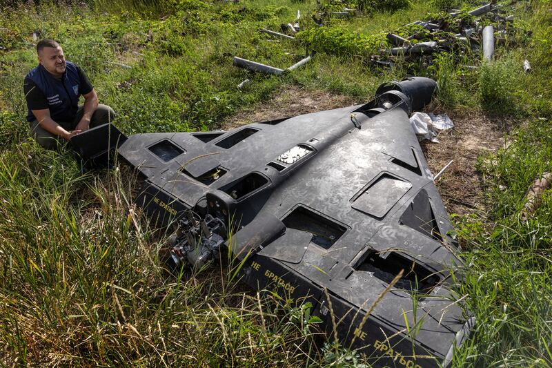 A Ukrainian official kneels by a downed Russian drone at a 'graveyard' for war ordnance in the Kharkiv region of Ukraine. While most of the ordnance are missiles, the weaponised drones are beginning to pile up. Photograph: David Guttenfelder/The New York Times
                      