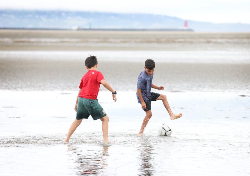 Best friends Denis Zele (11) in red and Karim Eldali (10) from Dublin 8 cool off with a kick around in the sea at Sandymount, Dublin. Photograph: Bryan O’Brien