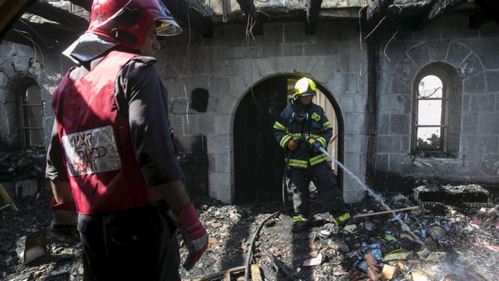 An Israeli fire fighter hoses down burnt leaflets in the Church of Loaves and Fishes on the shores of the Sea of Galilee, northern Israel on June 18th. Photograph: Baz Ratner/Reuters