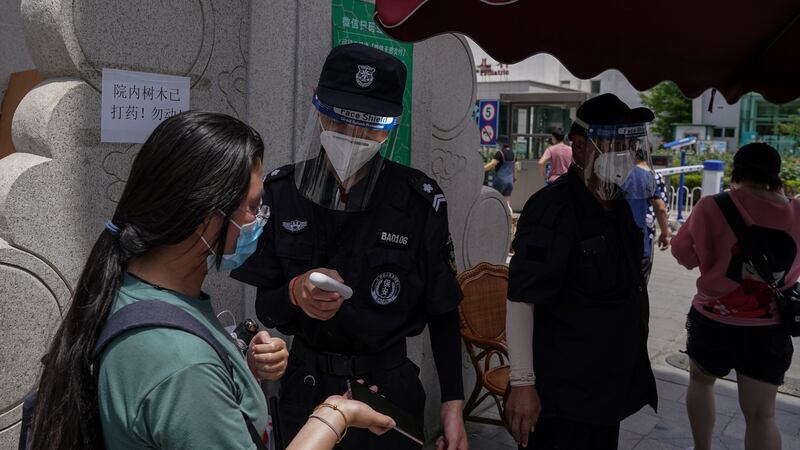 A security guard checks people’s temperature in Beijing. Photograph: EPA