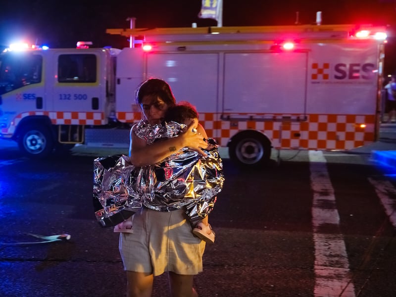 A woman leaves the scene with her child. Photograph: George Chan/Getty