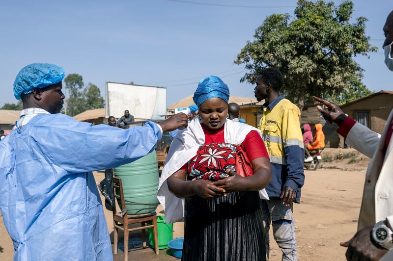 A health worker takes the temperature of a woman at a checkpoint in Bunia, Democratic Republic of the Congo. The outbreak is concentrated in Ituri, the war-torn province of which Bunia is the capital. Photograph: Arlette Bashizi/The New York Times
                      