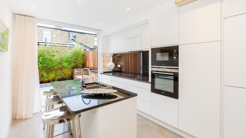 The kitchen  – white units topped with black granite – features an island.