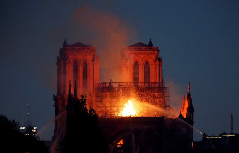Fire fighters douse flames of the burning Notre Dame Cathedral as the two rectangular towers are illuminated. Photograph: Charles Platiau/Reuters