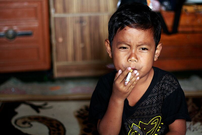 Dihan Awaiidan (7) takes a drag on his cigarette in Garut, West Java, Indonesia. He has been addicted to cigarettes since the age of just three. Photograph: Sijori Images / Barcroft India via Getty Images
