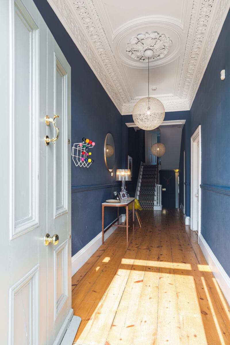 The hallway is painted a moody Farrow & Ball shade of dark blue