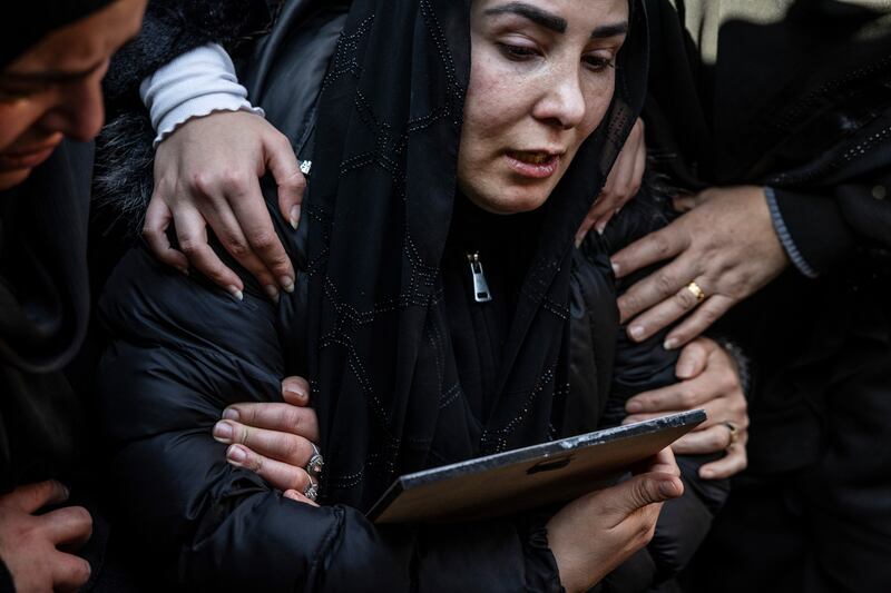 The widow of Ali Abed al Hussein al Khaffeji clutches a portrait of him as his body is placed in a grave. Photograph: David Guttenfelder/The New York Times
                      