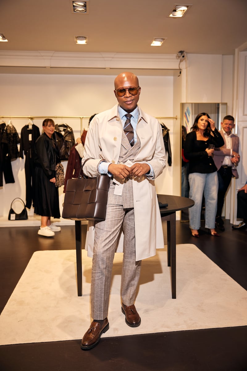Kwanele Nomoyi wears a trenchcoat from Icicle over a double-breasted pinstripe blazer from Louis Copeland, styled with an Eterne shirt, striped Tom Ford tie, brown Loake loafers and a Bottega Veneta tote. "The look was designed to transition easily between meetings during the day and events in the evening"
