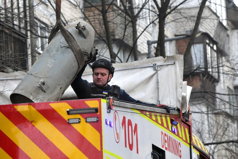 A Ukrainian explosives technician loads a fragment of a missile into a special demining armoured truck after a missile attack on Kyiv. Photograph:  Sergei Supinsky/AFP via Getty Images