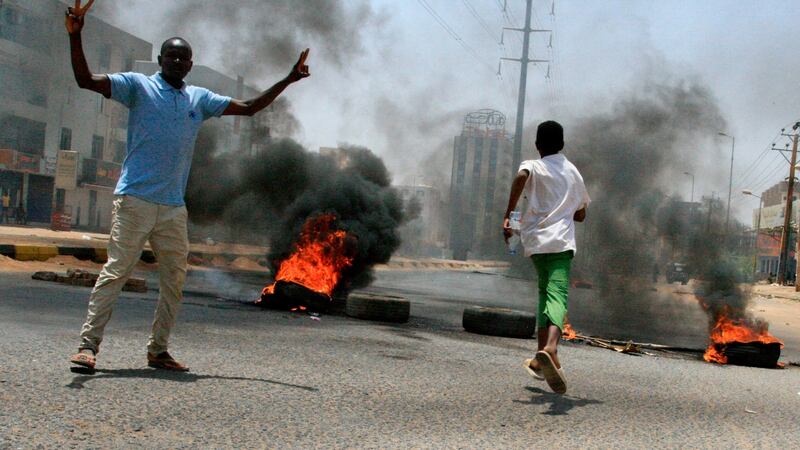 Sudanese protesters gesture as smoke billows from burning tires near Khartoum’s army headquarters. Photograph: Ebrahim Hamid/AFP/Getty Images