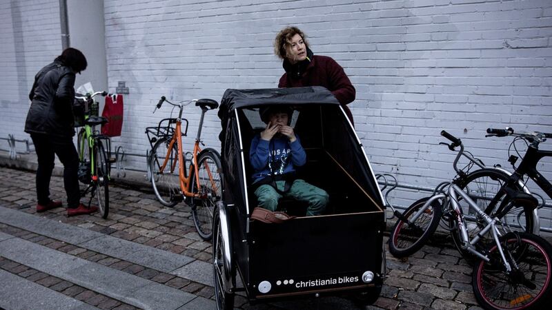 Natalie Gulsrud parks her cargo bike with her son, Pascal Rasmussen, outside a Copenhagen supermarket.  Photograph: Betina Garcia/The New York Times