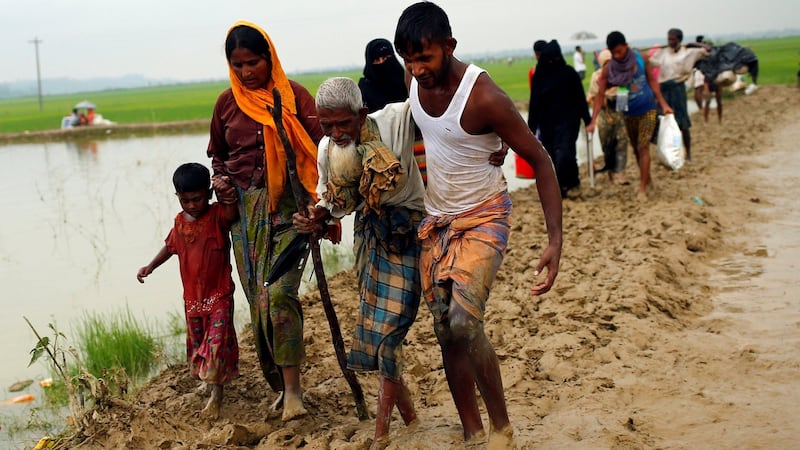Rohingya refugees walk on the muddy path after crossing the Bangladesh-Myanmar border in Teknaf, Bangladesh, on Sunday. Photograph:  Mohammad Ponir Hossain/Reuters