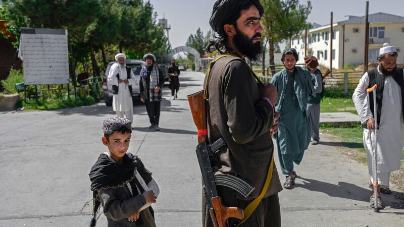 An Afghan boy and a member of the Taliban in front of the Pul-e-Charkhi prison in Kabul. Photograph:  Bulent Kilic/AFP via Getty Images