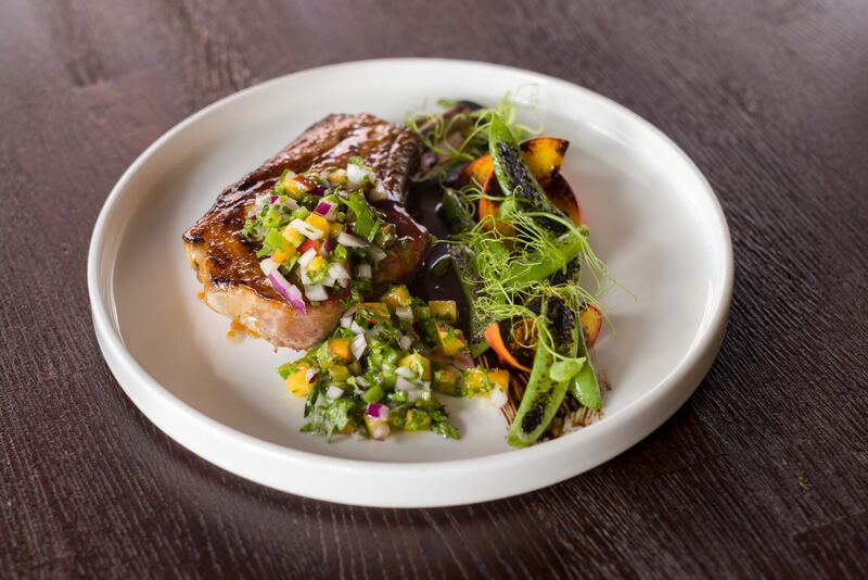 Char-grilled Andarl farm pork chop, peach, jalapeno, sugar snap and baby potatoes from the a la carte menu at Loretta’s.  
Photograph: John Ohle