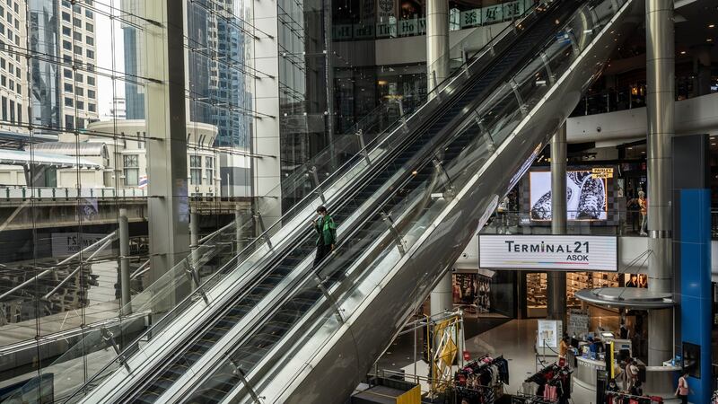 A food delivery worker rides down an escalator at a normally bustling shopping mall in Bangkok.  Photograph: Adam Dean/The New York Times
