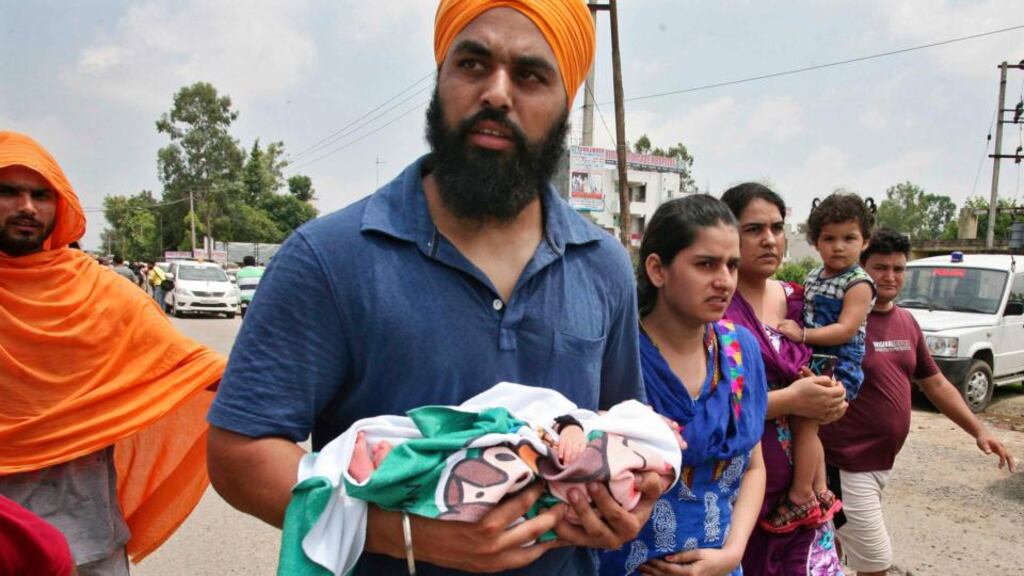 A man carries a newborn baby as he walks with his family after police said they were evacuated from a hospital near the site of a gunfight in Dinanagar town in the Gurdaspur district of Punjab, India, on Monday. Photograph: Munish Sharma/Reuters