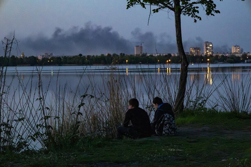 People sit by the Dnipro river, as smoke rises in the distance following a Russian air strike on the city on Tuesday. Photograph: Serhii Okunev/AFP via Getty