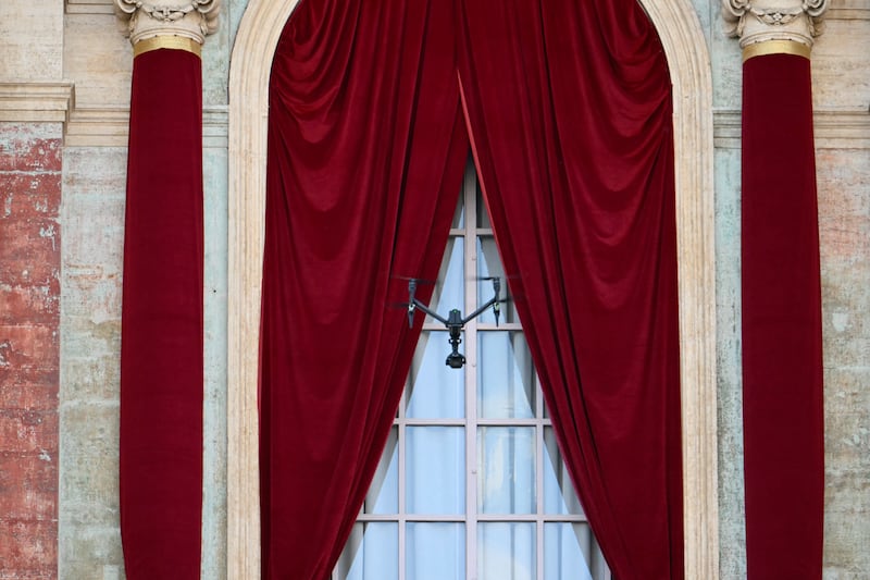 A drone flies in front of the window of the main central loggia balcony of the St Peter's Basilica, on the second day of the conclave. Photo by Alberto PIZZOLI / AFP.