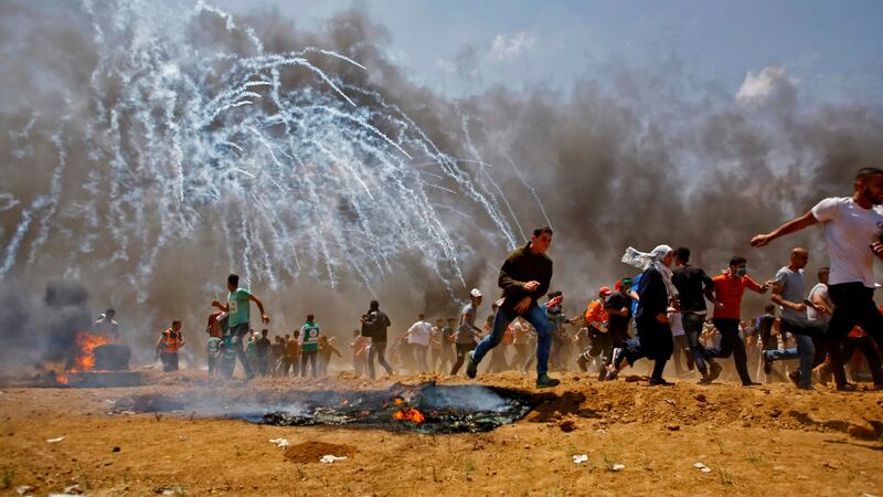 Palestinians run for cover from tear gas during clashes with Israeli security forces near the border between Israel and the Gaza Strip on Monday. Photograph:  Mohammed Abed/AFP/Getty Images