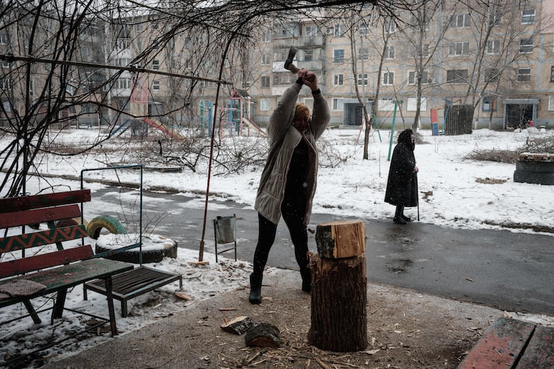 A woman chops firewood in front of her apartment building in Bakhmut, where there has been no electricity, heating or water for more than four months. Photograph: Yasuyoshi Chiba /Getty Images