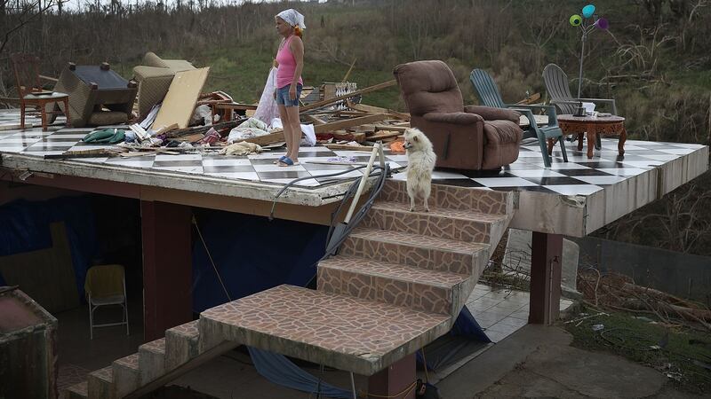 Irma Maldanado stands with  her parrot and her dog in what is left of her home in Corozal, Puerto Rico,  after it was destroyed  Hurricane Maria in September 2017. Photograph:   Joe Raedle/Getty Images