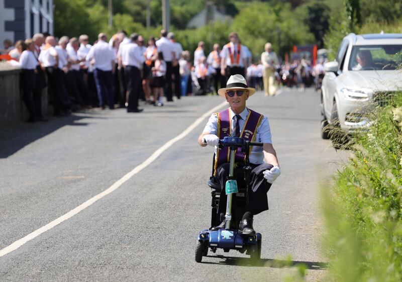 Samuel Parker from Larne arrives by mobility scooter at the assembly field  beside St John's Parish Church before taking part in the Orange Order parade in Rossnowlagh. Photo: Bryan O’Brien / The Irish Times   