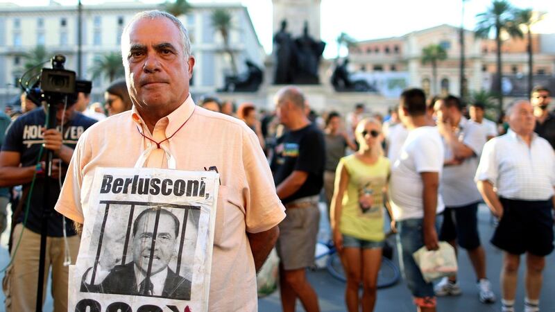 A man displays a poster depicting former Italian prime minister Silvio Berlusconi as he protests in front of Italy’s supreme court building in Rome. Photograph: Alessandro Bianchi/Reuters
