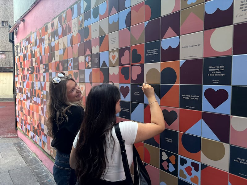 Friends Becky and Alannah, from Manchester, write their names on the wall at Love Lane, Temple Bar.  Photograph: Stephen Conneely